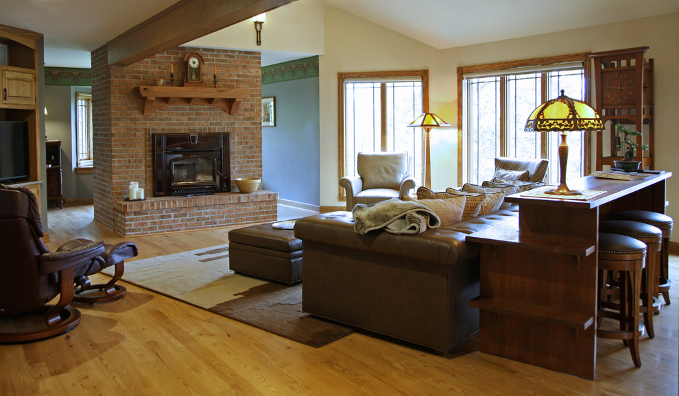 Example of a large arts and crafts loft-style light wood floor living room design in Milwaukee with yellow walls, a two-sided fireplace, a brick fireplace and a media wall