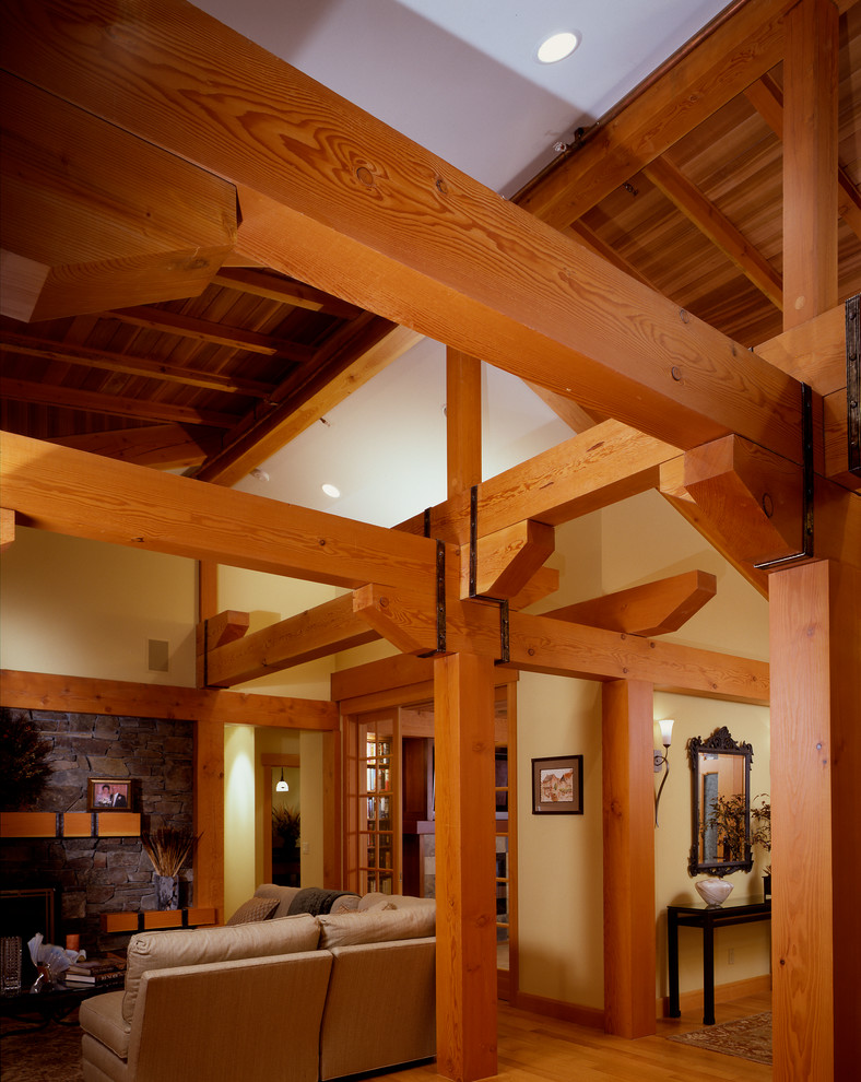 Modelo de salón abierto de estilo americano de tamaño medio con paredes beige, suelo de madera clara, todas las chimeneas y marco de chimenea de piedra