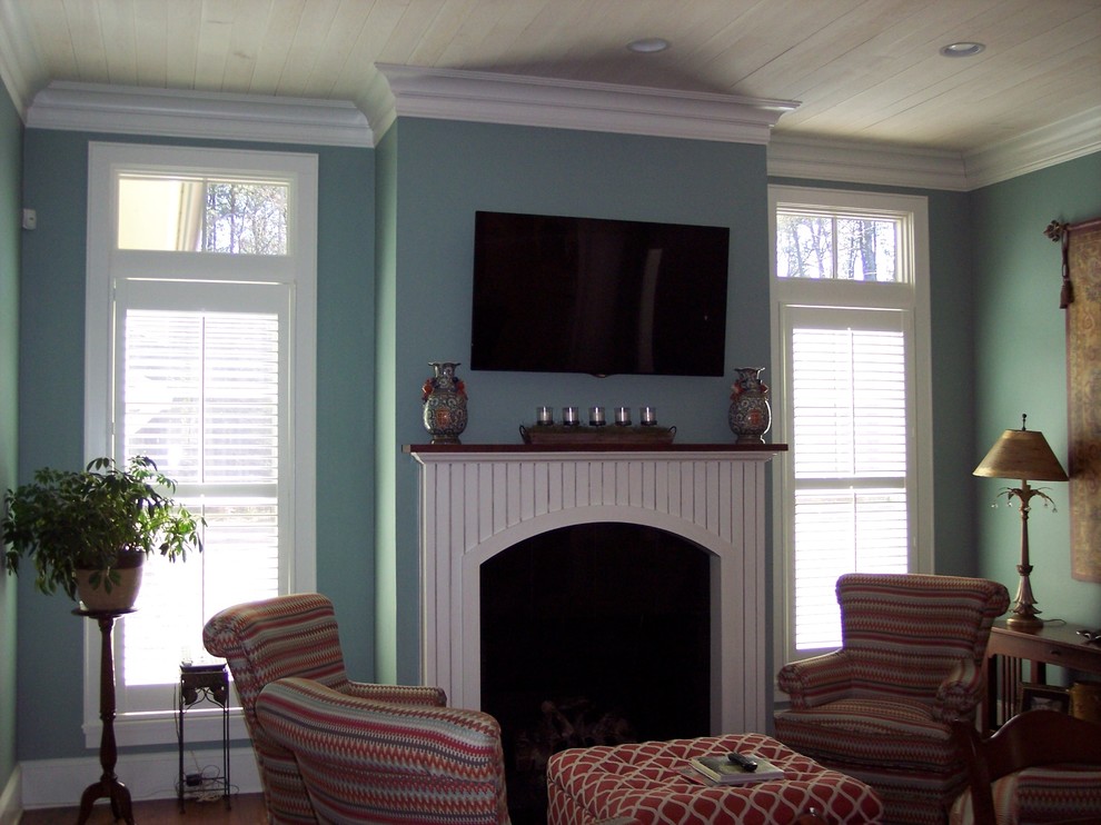 Idée de décoration pour un salon craftsman de taille moyenne et fermé avec une salle de réception, un mur bleu, parquet foncé, une cheminée standard, un manteau de cheminée en bois et un téléviseur fixé au mur.