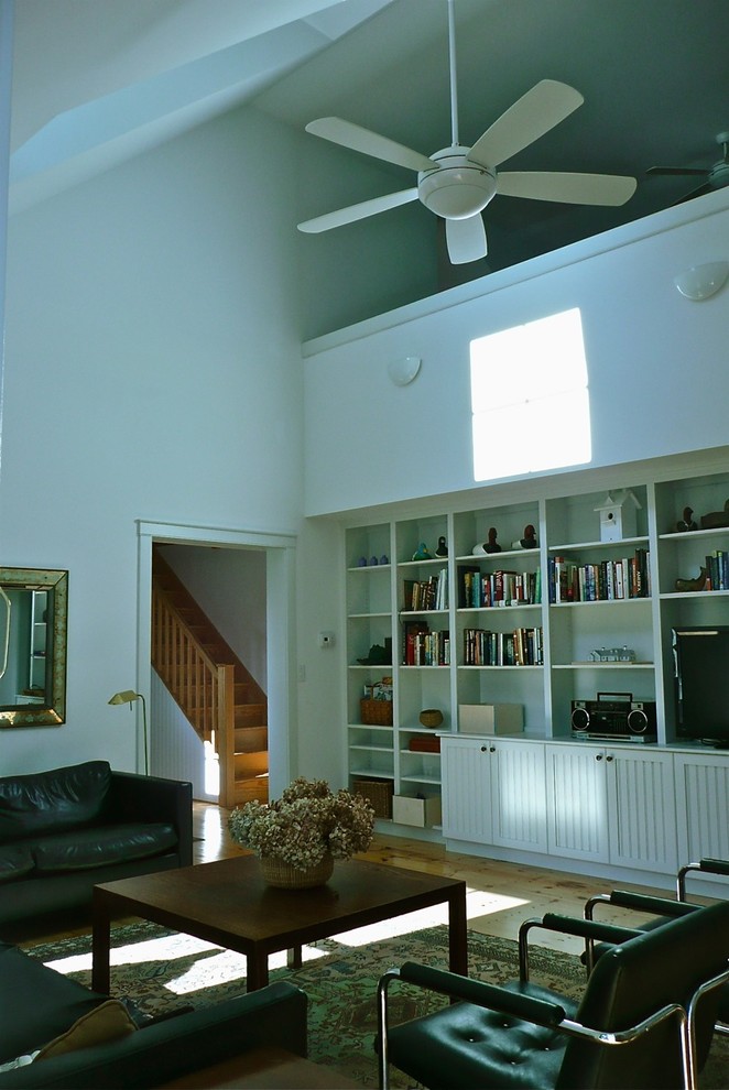 Klassisk inredning av ett mellanstort allrum med öppen planlösning, med ett finrum, vita väggar, mellanmörkt trägolv, en fristående TV och brunt golv