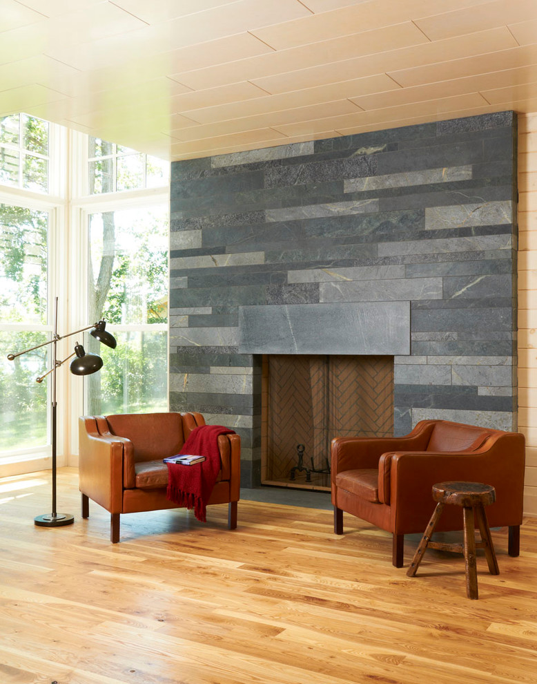 Aménagement d'un salon moderne avec un sol en bois brun et un manteau de cheminée en pierre.
