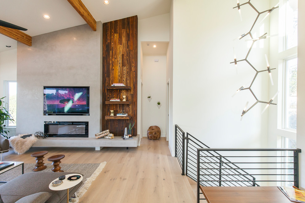 Photo of a medium sized modern open plan living room in Austin with white walls, light hardwood flooring, a standard fireplace, a plastered fireplace surround and a built-in media unit.
