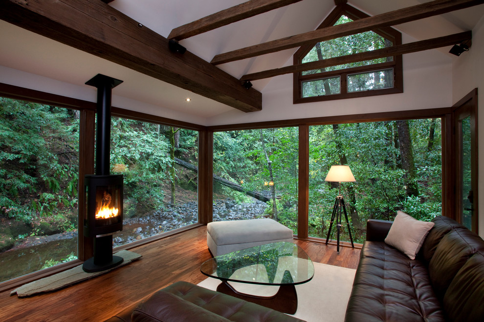 Exemple d'un salon montagne de taille moyenne et ouvert avec un mur blanc, un sol en bois brun, un manteau de cheminée en pierre et un téléviseur dissimulé.