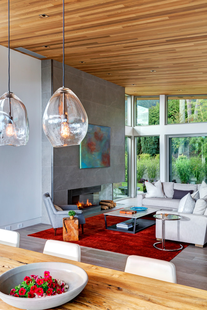 Großes, Offenes Modernes Wohnzimmer mit braunem Holzboden, Kamin, gefliester Kaminumrandung und verstecktem TV in Vancouver