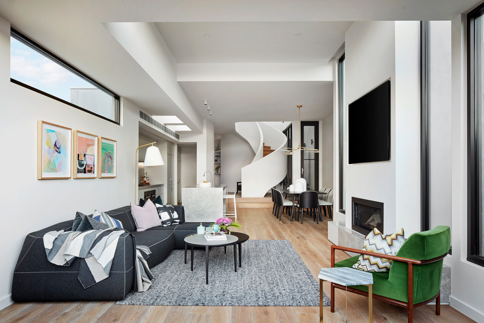 На фото: открытая гостиная комната в современном стиле с белыми стенами, светлым паркетным полом, горизонтальным камином и телевизором на стене с