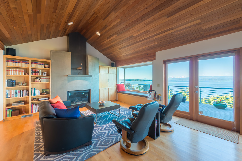 Foto de salón abierto actual con paredes grises, suelo de madera en tonos medios, todas las chimeneas, televisor retractable y suelo marrón