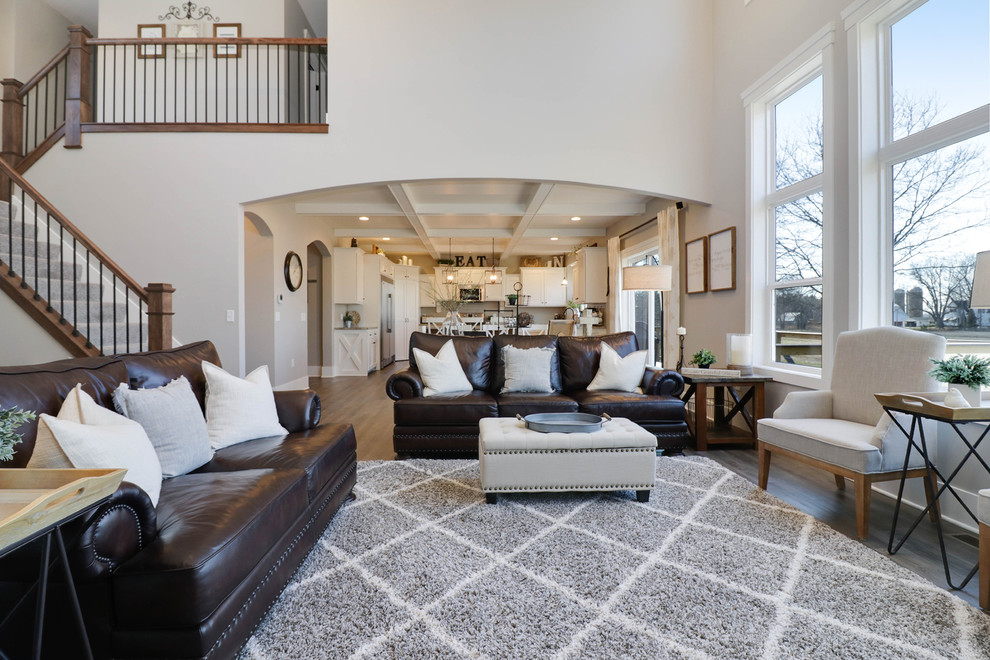 Photo of a large country formal open plan living room in Grand Rapids with grey walls, medium hardwood flooring, a standard fireplace, a stone fireplace surround, a wall mounted tv and brown floors.