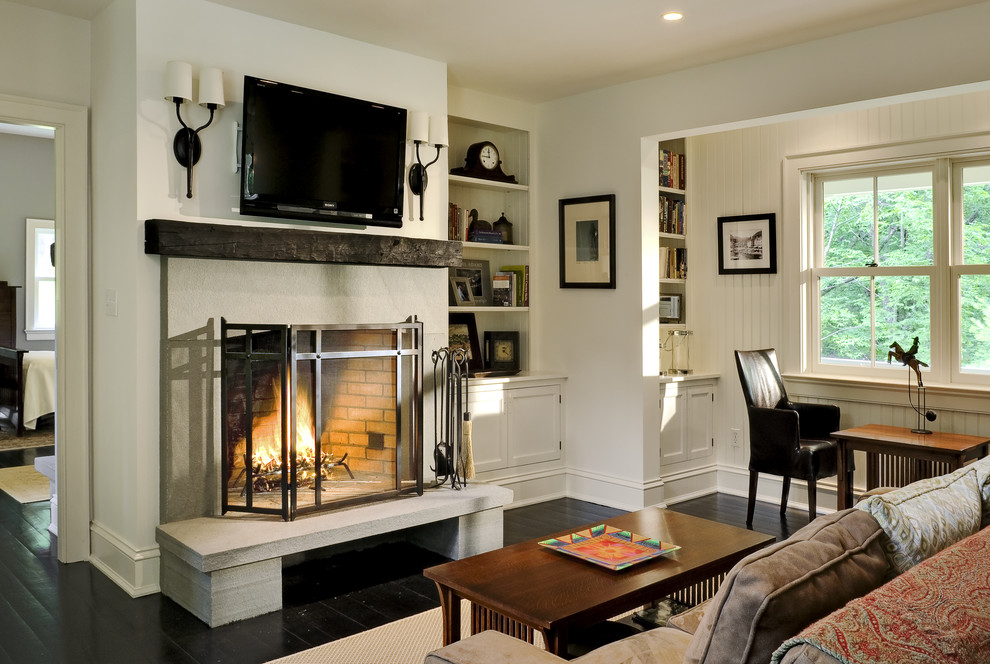 Classic living room in New York with dark hardwood flooring, a standard fireplace, a wall mounted tv and black floors.