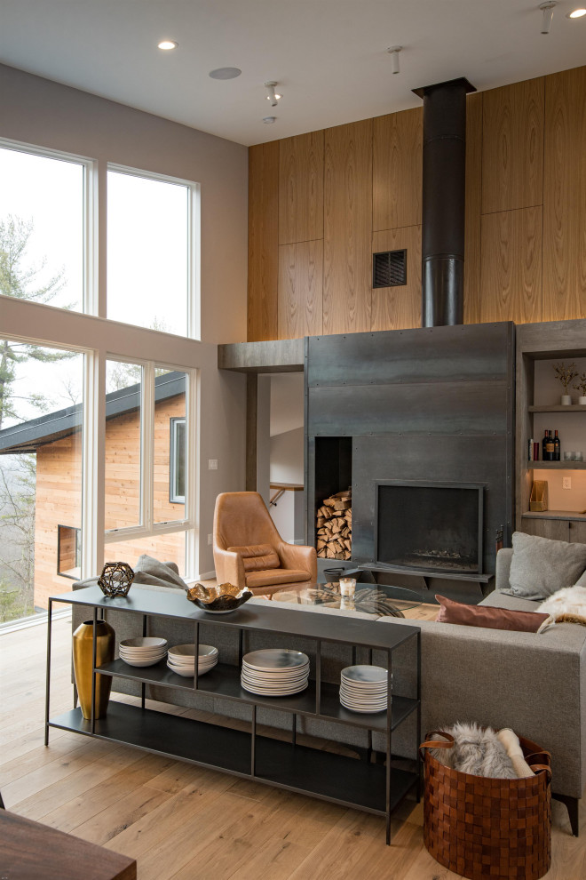 Cette image montre un salon design ouvert avec un manteau de cheminée en métal.