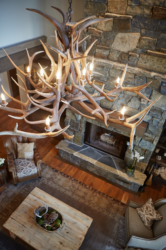 Rustic open plan living room in Grand Rapids with brown walls, medium hardwood flooring, a standard fireplace, a stone fireplace surround and a built-in media unit.