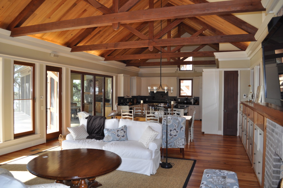 Immagine di un grande soggiorno minimal aperto con pareti beige, pavimento in legno massello medio e TV a parete