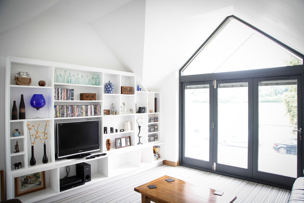 Пример оригинального дизайна: двухуровневая гостиная комната в современном стиле с с книжными шкафами и полками, белыми стенами и ковровым покрытием