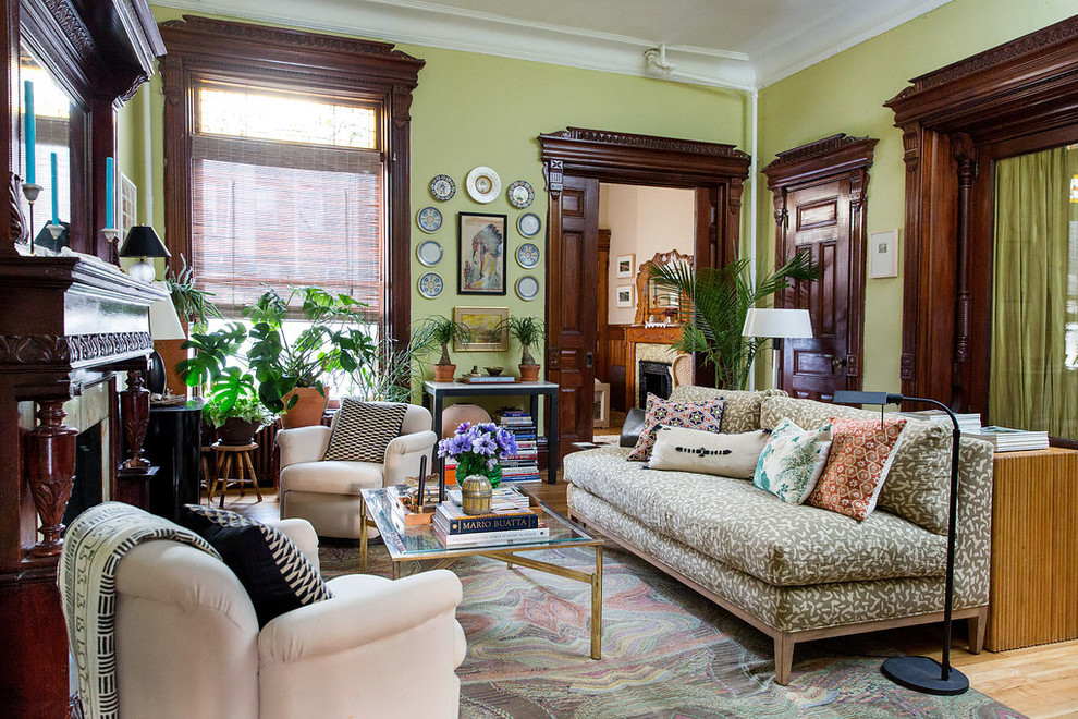 Design ideas for an eclectic living room in New York with green walls and light hardwood flooring.