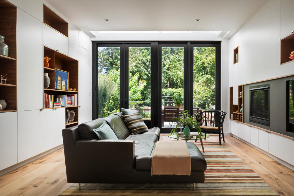 Offenes Modernes Wohnzimmer mit hellem Holzboden, Kamin und Multimediawand in New York