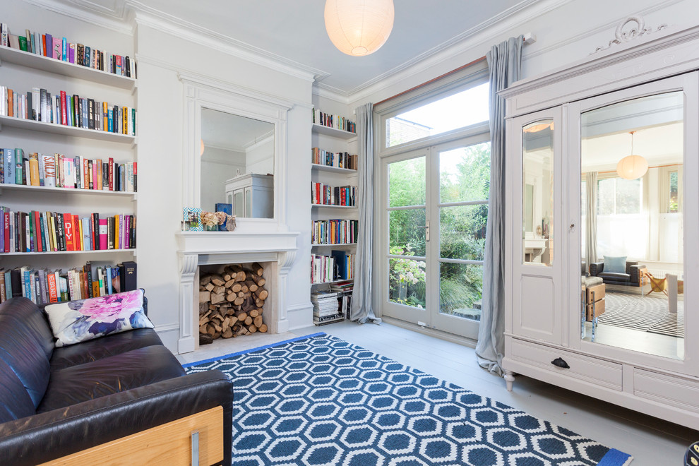 Идея дизайна: изолированная гостиная комната в скандинавском стиле с с книжными шкафами и полками, серыми стенами, деревянным полом и стандартным камином