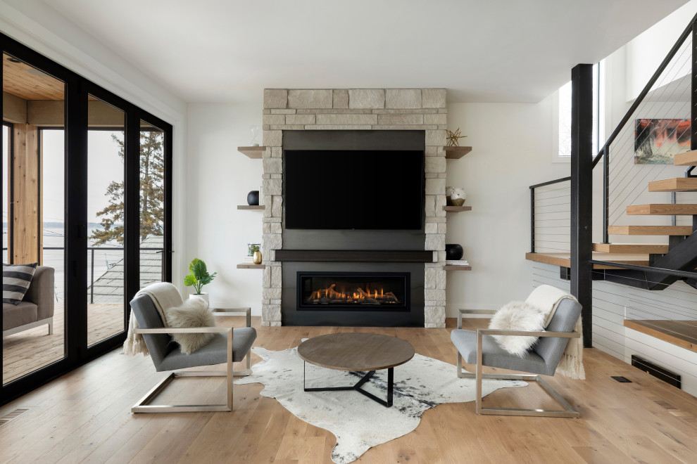 ミネアポリスにあるコンテンポラリースタイルのおしゃれなLDK (白い壁、無垢フローリング、横長型暖炉、石材の暖炉まわり、壁掛け型テレビ、茶色い床) の写真