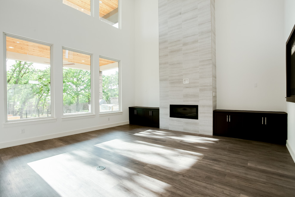 Cette photo montre un grand salon moderne ouvert avec un mur blanc, un manteau de cheminée en carrelage, un sol marron et une cheminée standard.