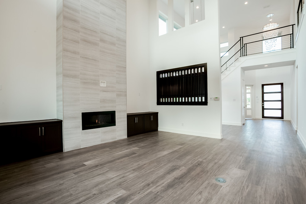 Großes, Offenes Modernes Wohnzimmer mit weißer Wandfarbe, braunem Holzboden, Gaskamin, gefliester Kaminumrandung, TV-Wand und braunem Boden in Dallas