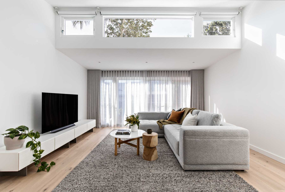 Cette image montre un salon design ouvert avec un mur blanc, un sol en bois brun, aucune cheminée, un téléviseur indépendant et un sol marron.