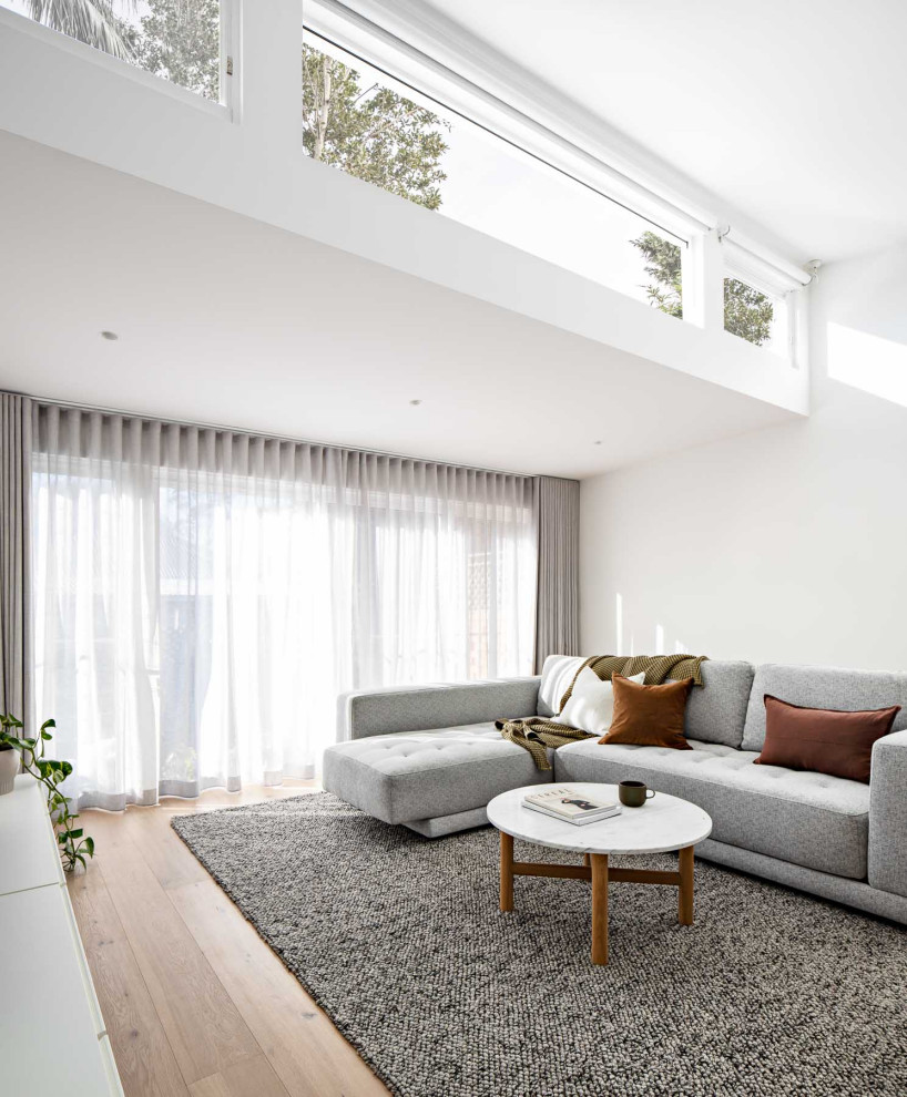 Exempel på ett stort modernt allrum med öppen planlösning, med vita väggar, ljust trägolv och en väggmonterad TV
