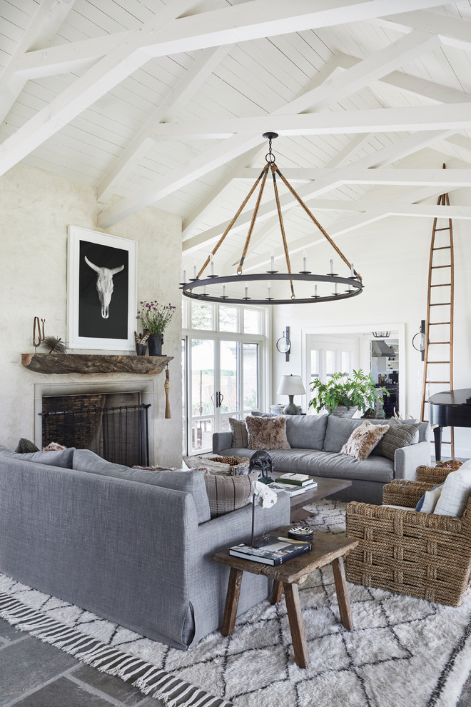 Immagine di un soggiorno country aperto con pareti bianche, camino classico e pavimento grigio