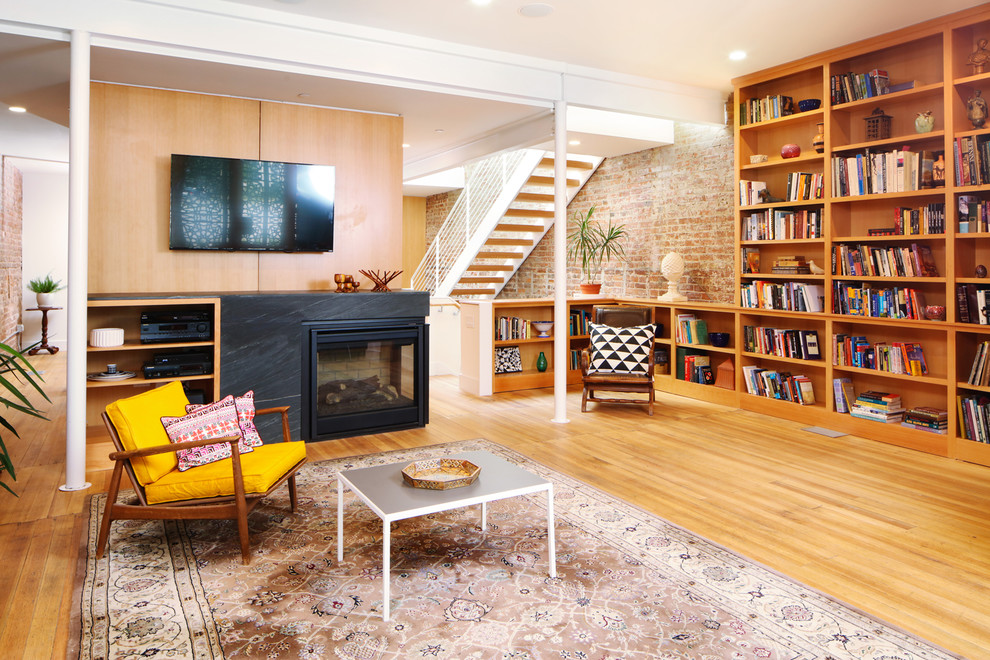 Esempio di un soggiorno design aperto con pavimento in legno massello medio, camino classico, TV a parete e pavimento marrone