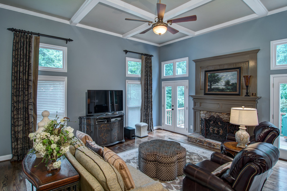 Mittelgroßes Klassisches Wohnzimmer mit blauer Wandfarbe, braunem Holzboden, Kamin, Kaminumrandung aus Holz und freistehendem TV in Atlanta