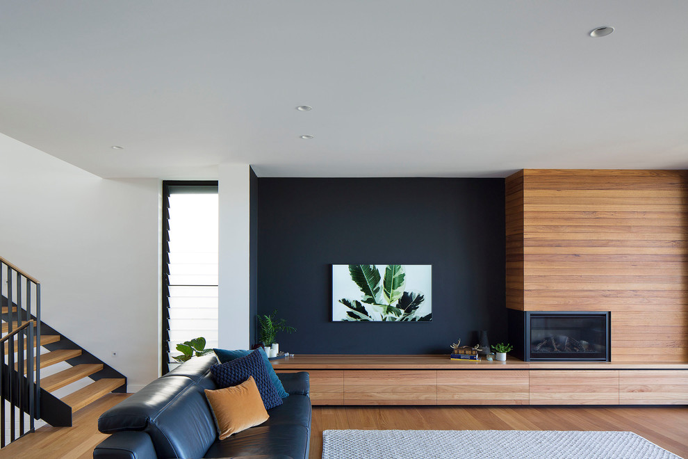 На фото: гостиная комната в современном стиле с синими стенами, паркетным полом среднего тона, стандартным камином, фасадом камина из дерева и коричневым полом