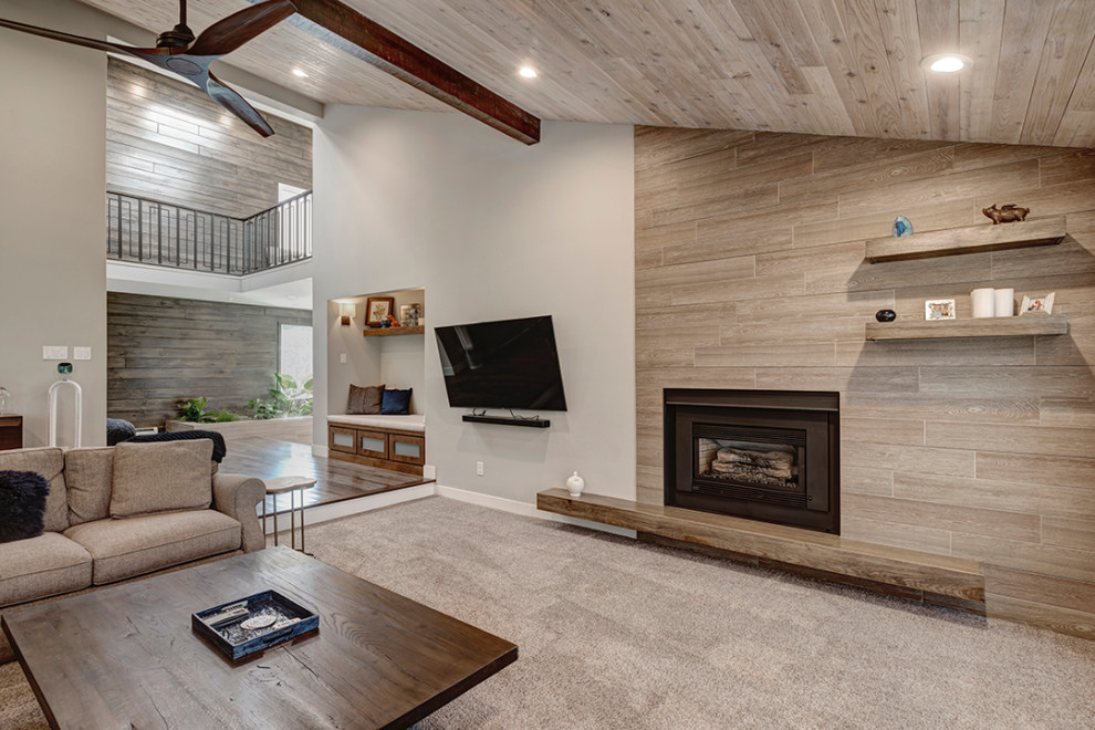 デンバーにある高級な広いミッドセンチュリースタイルのおしゃれなLDK (ベージュの壁、カーペット敷き、標準型暖炉、木材の暖炉まわり、壁掛け型テレビ、ベージュの床、三角天井) の写真