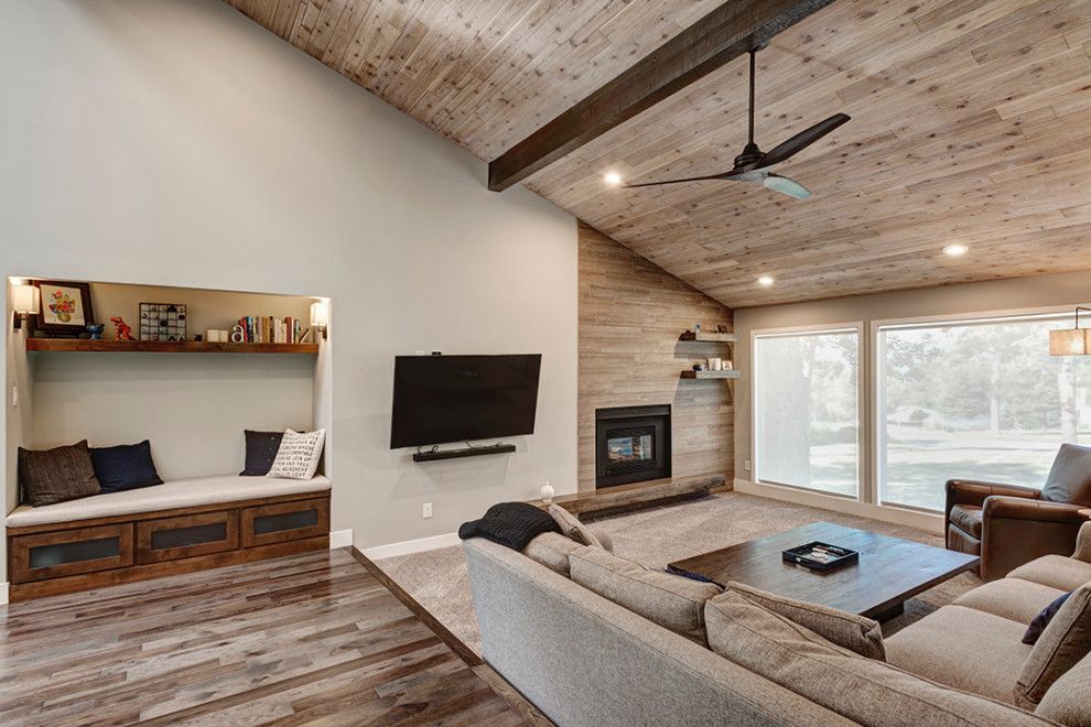 Inspiration for a large 1950s open concept carpeted, beige floor and vaulted ceiling living room remodel in Denver with beige walls, a standard fireplace, a wood fireplace surround and a wall-mounted tv