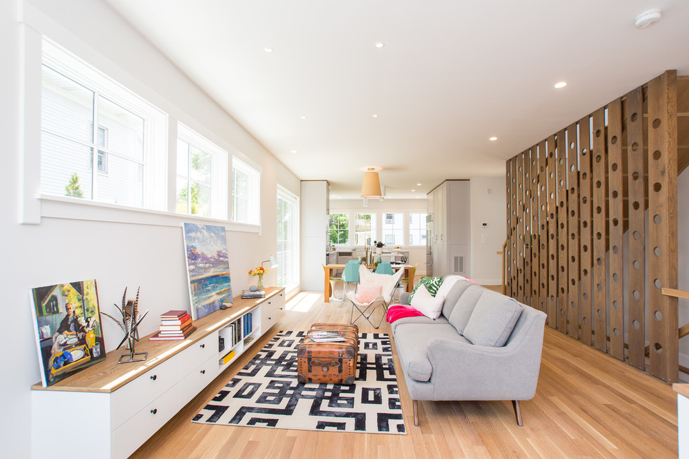 Modelo de salón abierto bohemio sin televisor con paredes blancas, suelo de madera clara y suelo beige