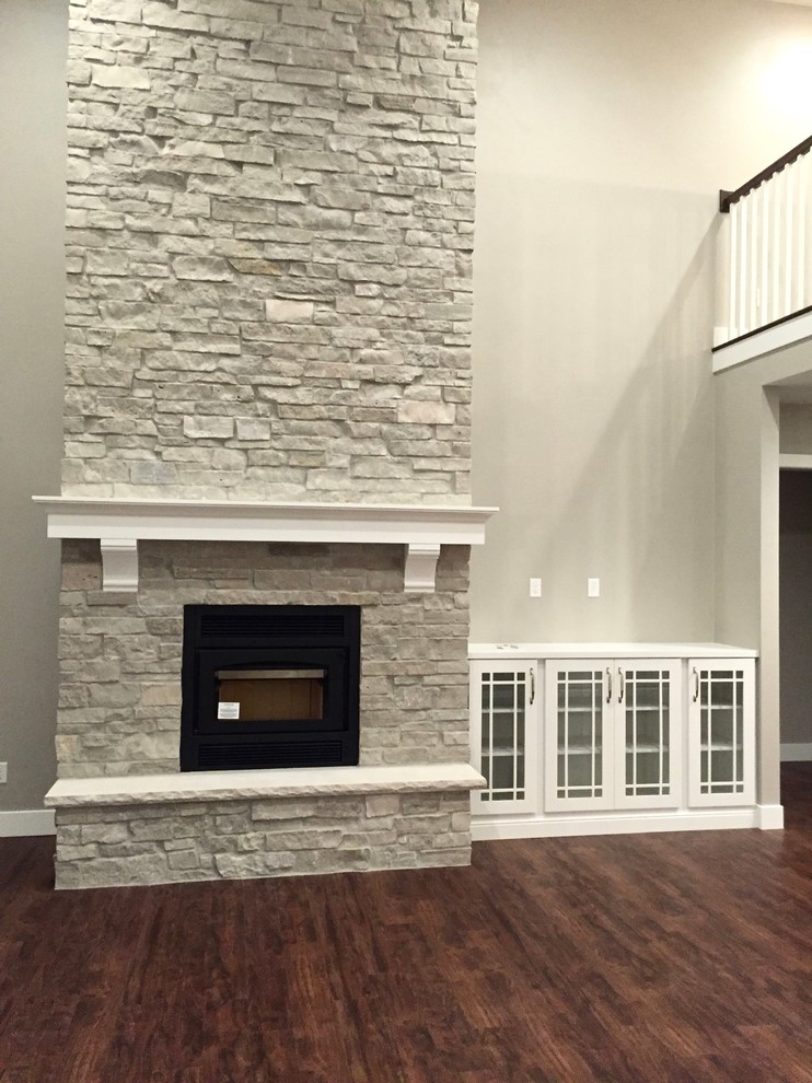 Cette photo montre un salon tendance de taille moyenne et ouvert avec un mur gris, une cheminée standard, un manteau de cheminée en pierre et un téléviseur encastré.