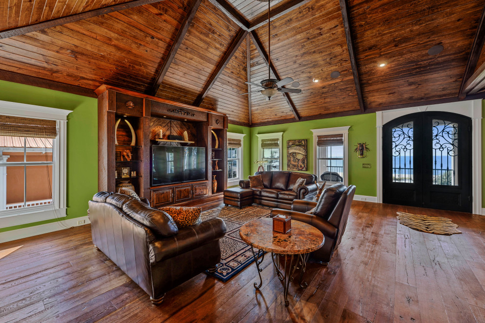 Großes, Offenes Maritimes Wohnzimmer ohne Kamin mit grüner Wandfarbe, braunem Holzboden, freistehendem TV, braunem Boden und Holzdecke in Sonstige