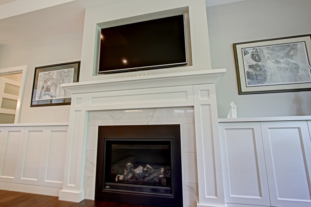 Photo of a medium sized classic formal open plan living room in Toronto with grey walls, dark hardwood flooring, a standard fireplace, a tiled fireplace surround, a wall mounted tv and brown floors.
