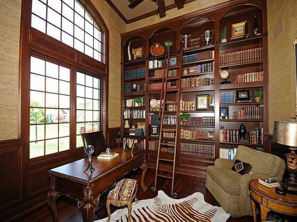 Imagen de despacho tradicional grande con biblioteca y suelo de madera oscura