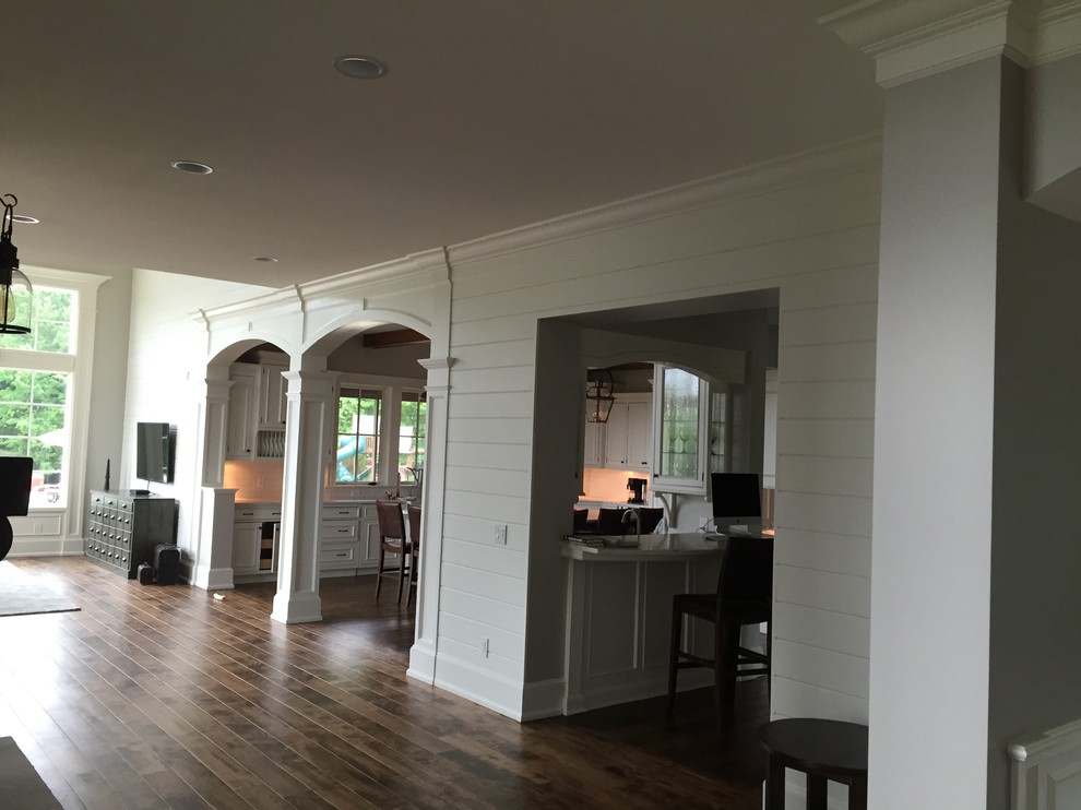 Ejemplo de salón abierto clásico renovado grande con paredes grises, suelo de madera en tonos medios y televisor colgado en la pared