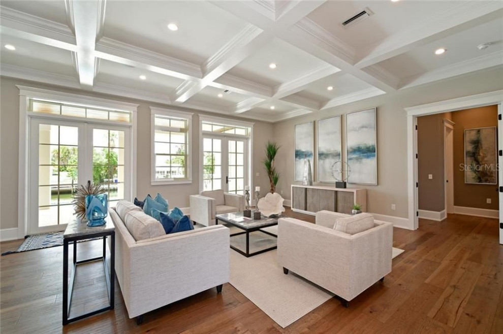 Idee per un soggiorno stile marinaro aperto con pareti beige, pavimento in legno massello medio, pavimento marrone e soffitto ribassato