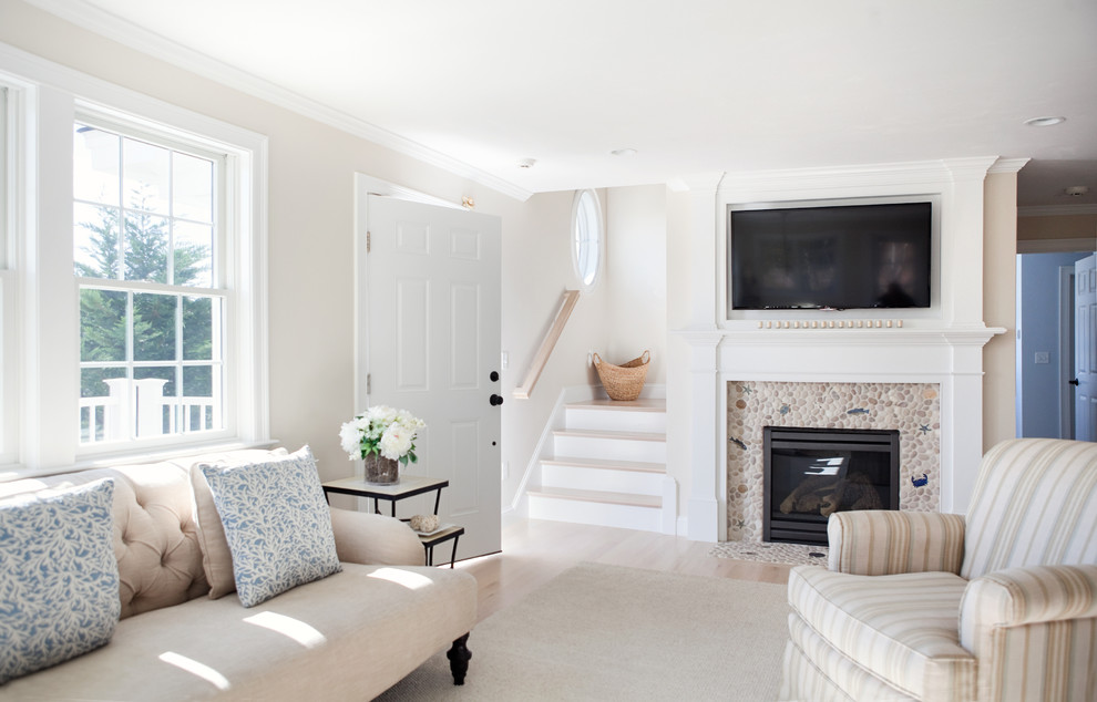 Offenes Maritimes Wohnzimmer mit beiger Wandfarbe, Kamin, gefliester Kaminumrandung, TV-Wand und hellem Holzboden in Boston