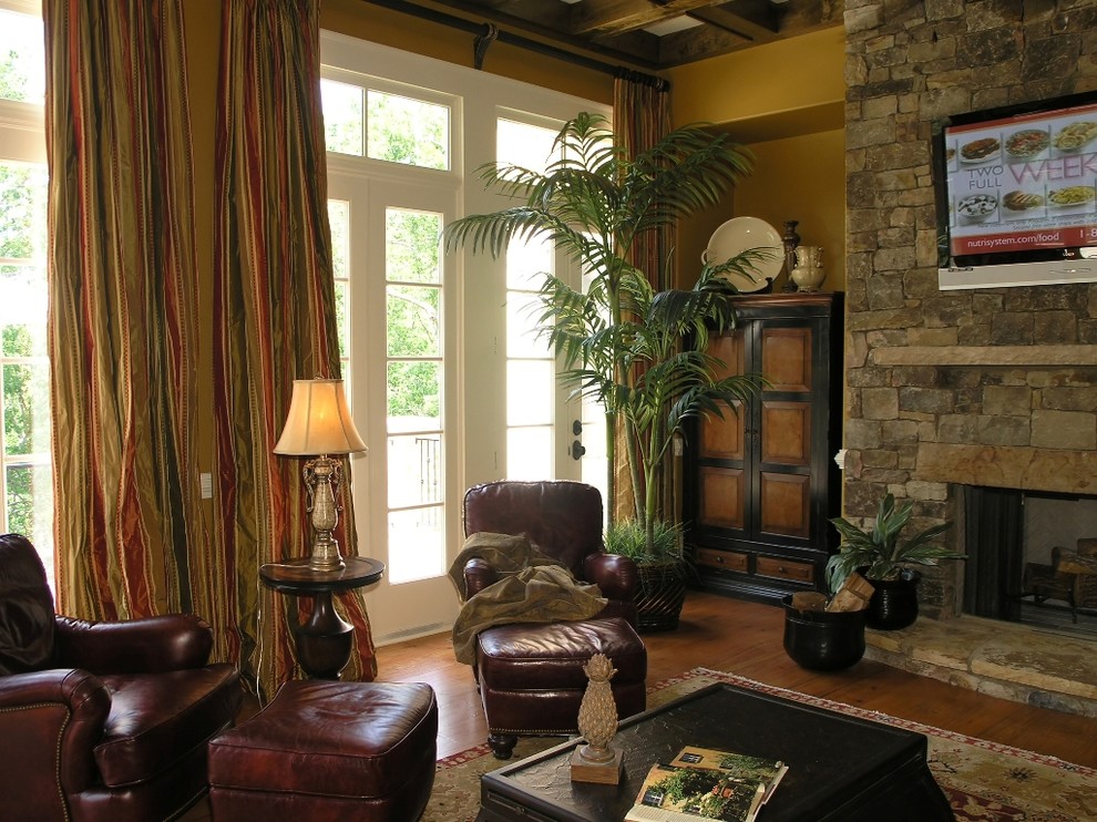 Ejemplo de salón clásico de tamaño medio con paredes marrones, suelo de madera en tonos medios, todas las chimeneas, marco de chimenea de piedra, televisor colgado en la pared y suelo marrón