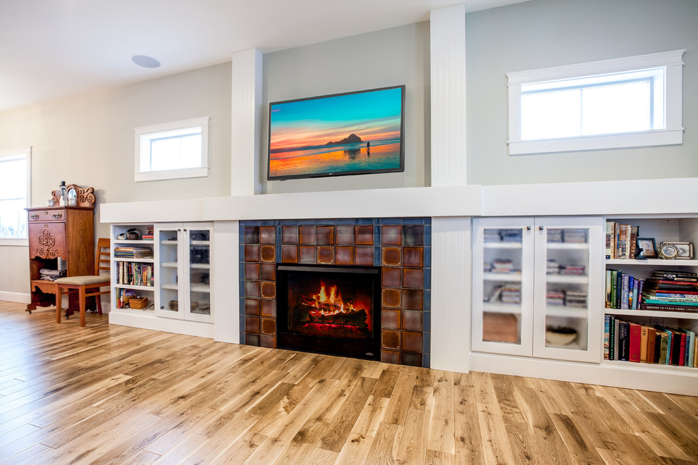 Inspiration for a mid-sized craftsman open concept light wood floor and white floor living room library remodel in Albuquerque with gray walls, a standard fireplace, a tile fireplace and a wall-mounted tv