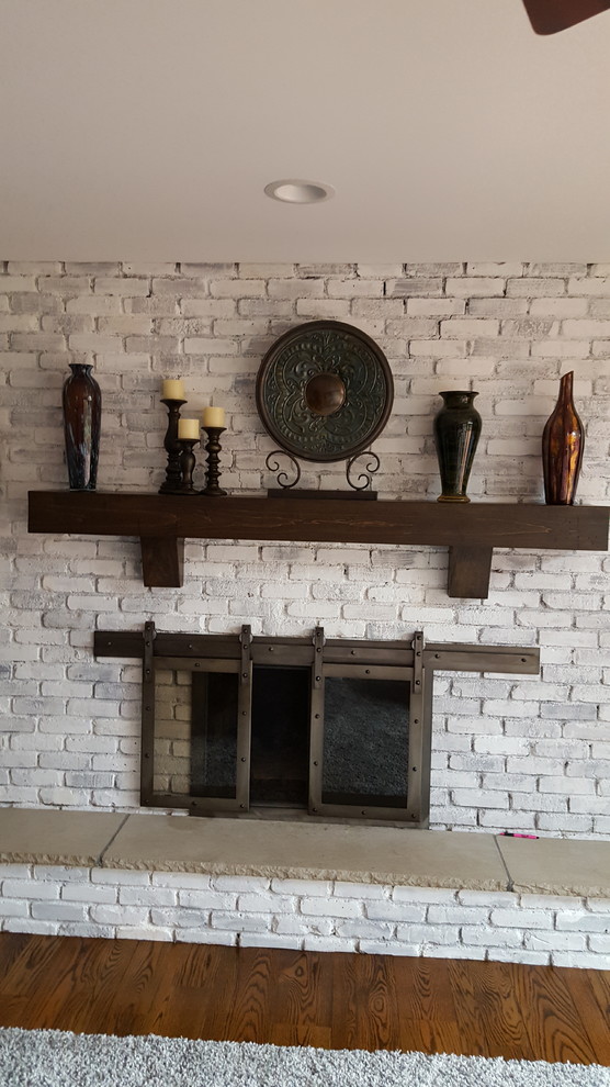 他の地域にあるお手頃価格の中くらいなトランジショナルスタイルのおしゃれなLDK (白い壁、無垢フローリング、標準型暖炉、レンガの暖炉まわり、白い床) の写真