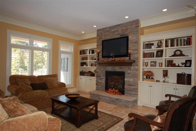 Photo of a large traditional formal enclosed living room in Calgary with yellow walls, ceramic flooring, a standard fireplace, a stone fireplace surround and a wall mounted tv.