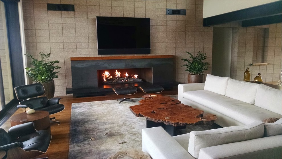 Großes Modernes Wohnzimmer mit grauer Wandfarbe, braunem Holzboden, Gaskamin und Kaminumrandung aus Holz in Phoenix