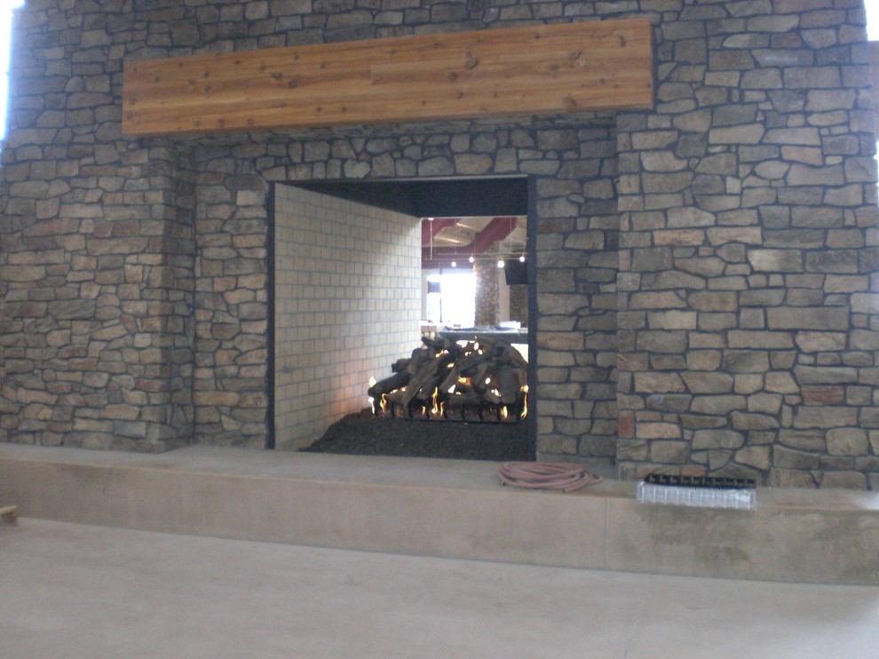 Elegant living room photo in Denver with a two-sided fireplace and a stone fireplace