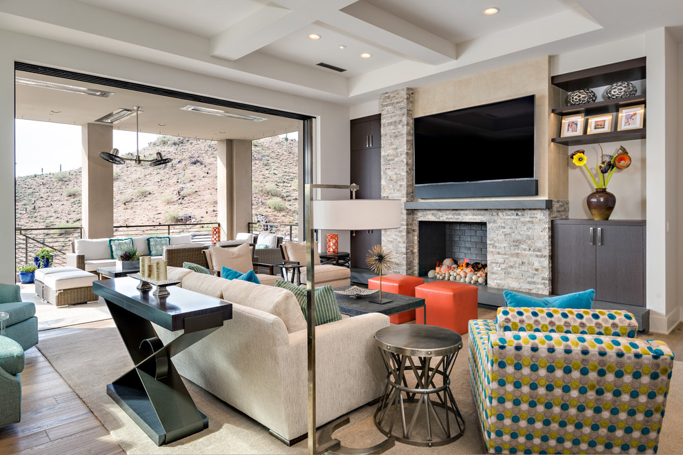 Пример оригинального дизайна: открытая гостиная комната в стиле неоклассика (современная классика) с стандартным камином, фасадом камина из камня и телевизором на стене