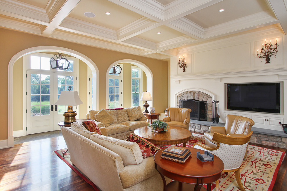 Großes, Offenes Klassisches Wohnzimmer mit beiger Wandfarbe, braunem Holzboden, Kamin, Kaminumrandung aus Stein und TV-Wand in Philadelphia