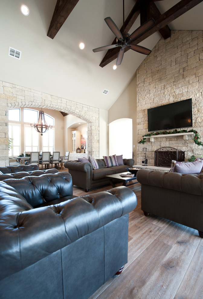 Inspiration for a timeless open concept light wood floor living room remodel in Austin with a stone fireplace and a wall-mounted tv