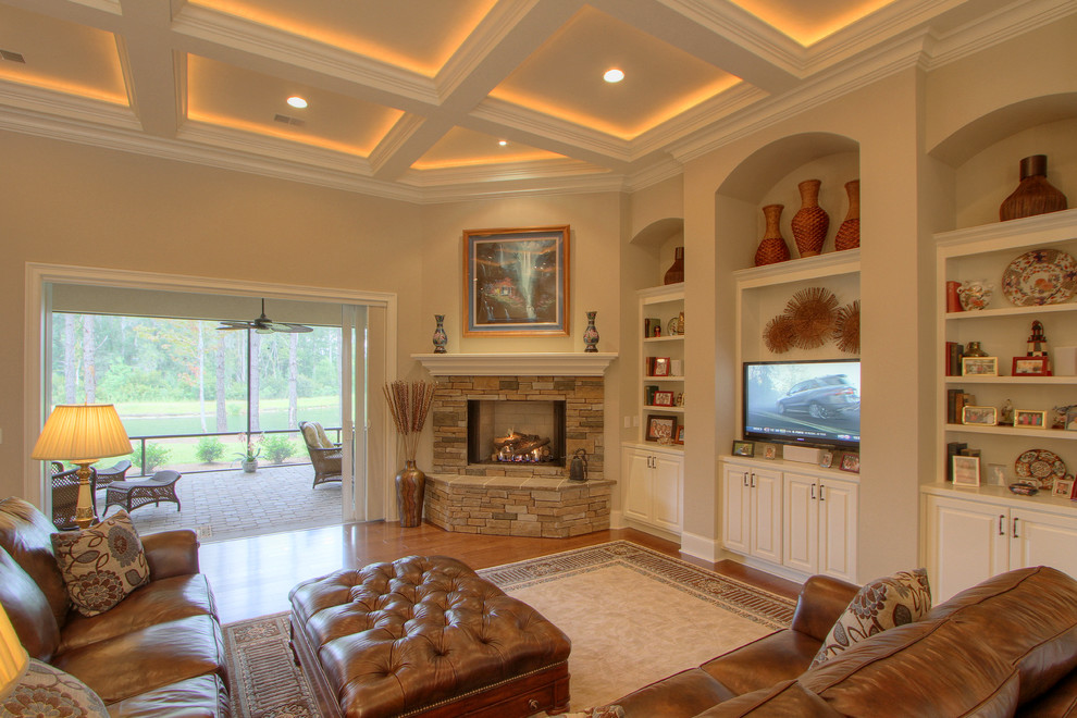 Design ideas for a large beach style formal mezzanine living room in Atlanta with beige walls, a corner fireplace, medium hardwood flooring, a stone fireplace surround, a built-in media unit and feature lighting.