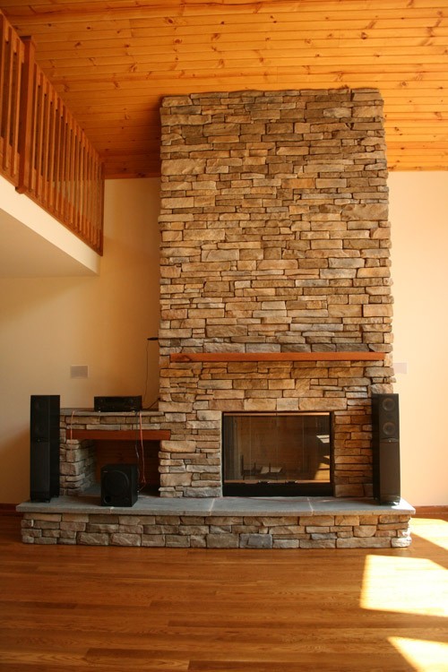 Cette image montre un salon craftsman de taille moyenne et ouvert avec un mur beige, une cheminée standard, un manteau de cheminée en pierre et un sol marron.