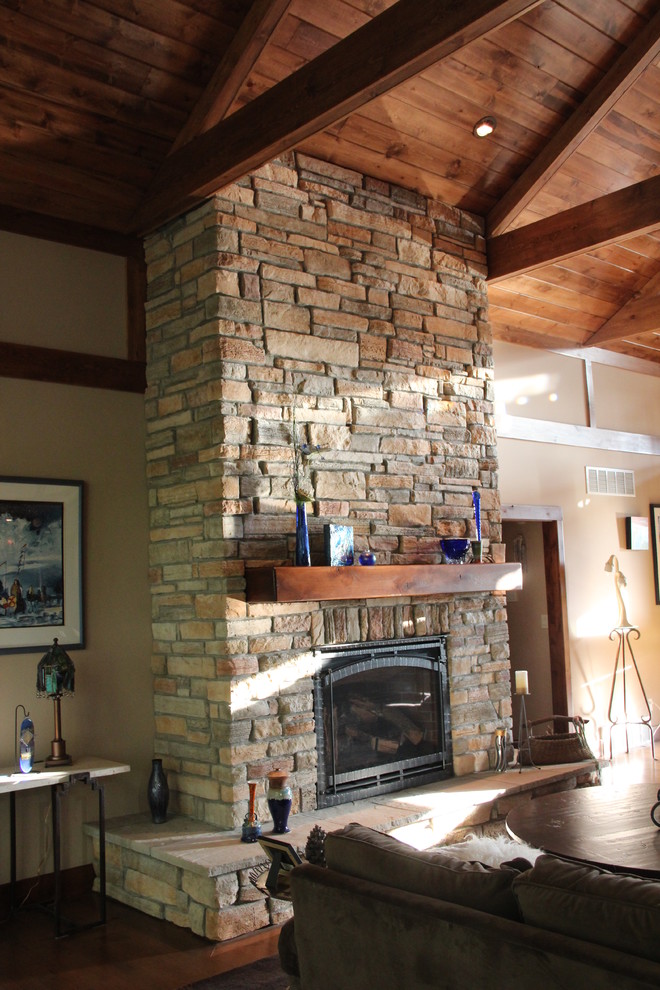 Inspiration pour un grand salon chalet avec parquet clair, une cheminée standard et un manteau de cheminée en pierre.